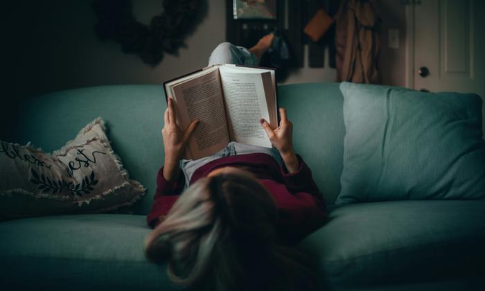A person reading a book while relaxing on a couch