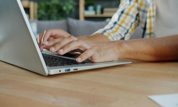 Close-up of hands typing on a laptop keyboard